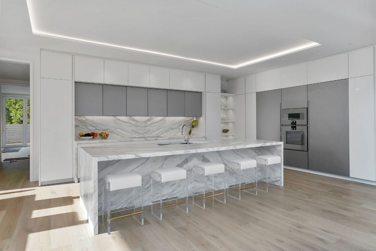 Kitchen features a marble waterfall island, integrated appliances, and minimalist cabinetry for a sophisticated touch.