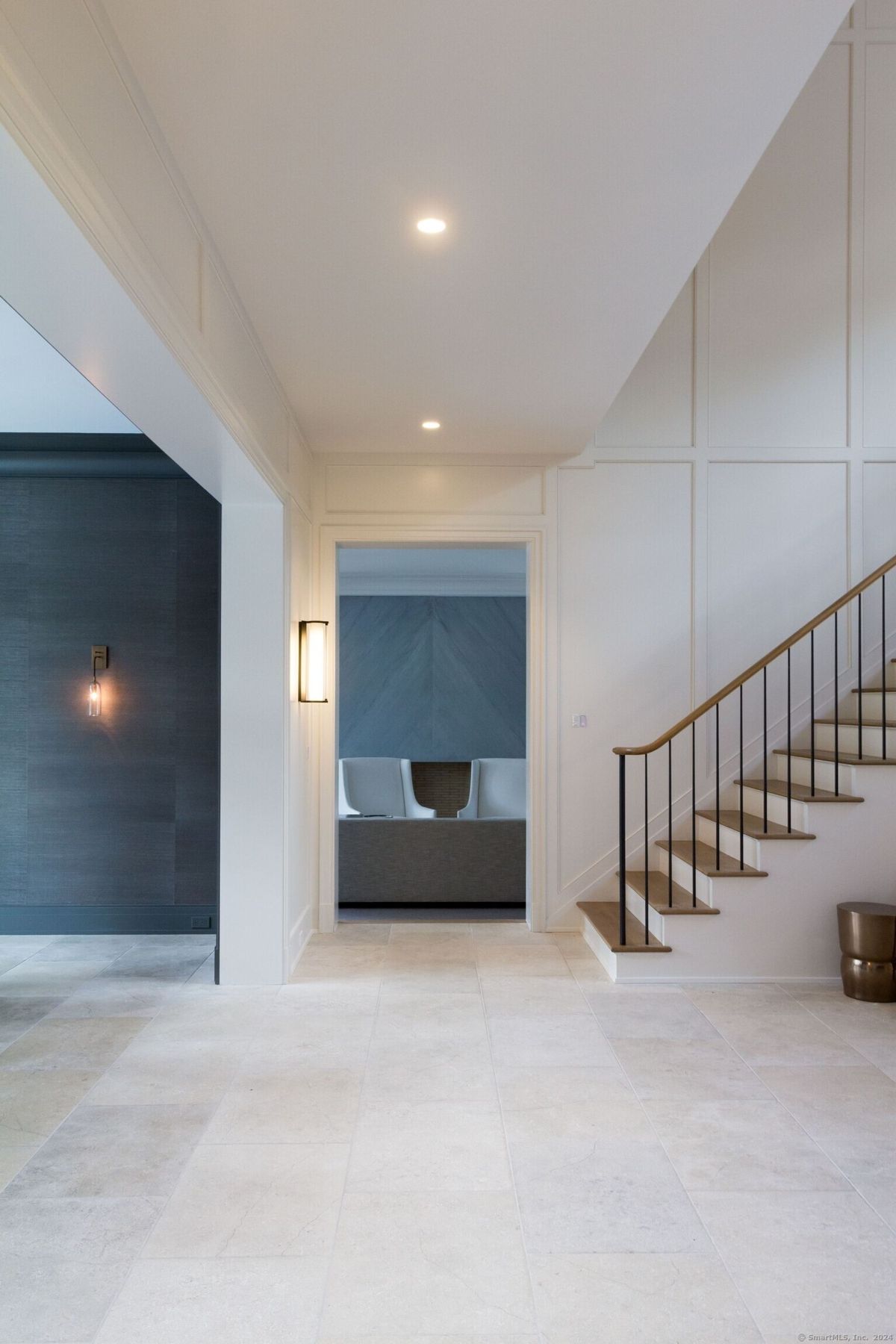 Hallway features a modern staircase and a glimpse of a seating area.