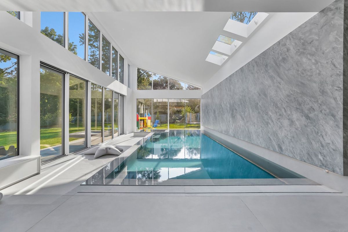 Indoor lap pool design features floor-to-ceiling windows and a textured wall.