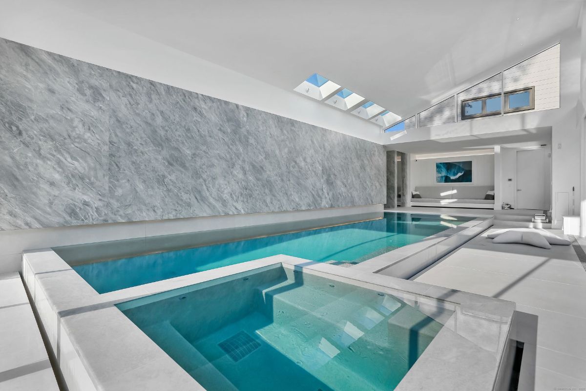 Indoor pool area features a large pool, a smaller spa, and a skylight.