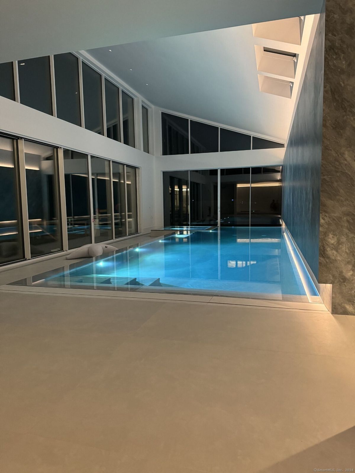 Luminous indoor pool area features a sleek design and floor-to-ceiling windows.