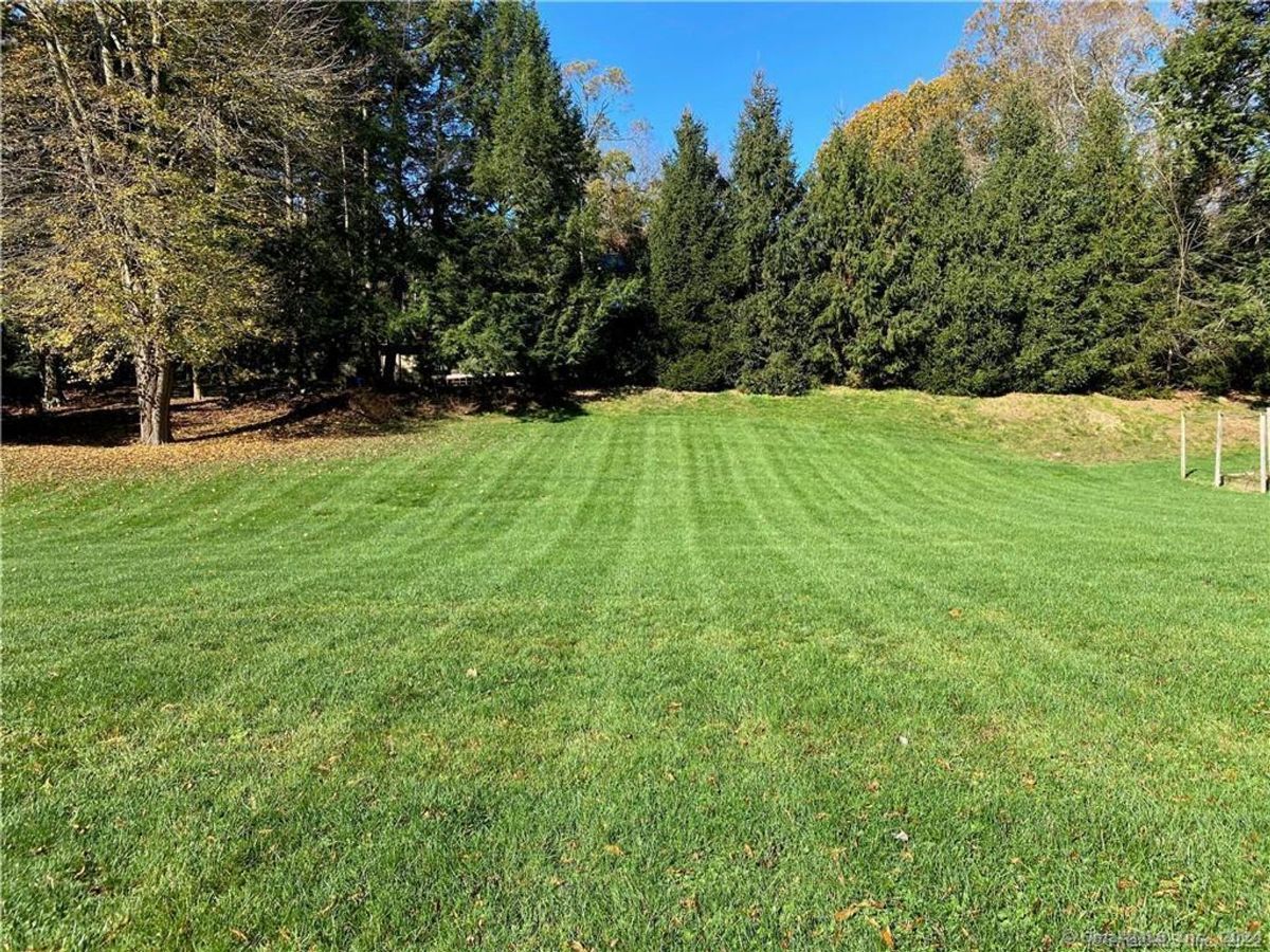 Landscaped yard features neatly mowed grass and a backdrop of trees.