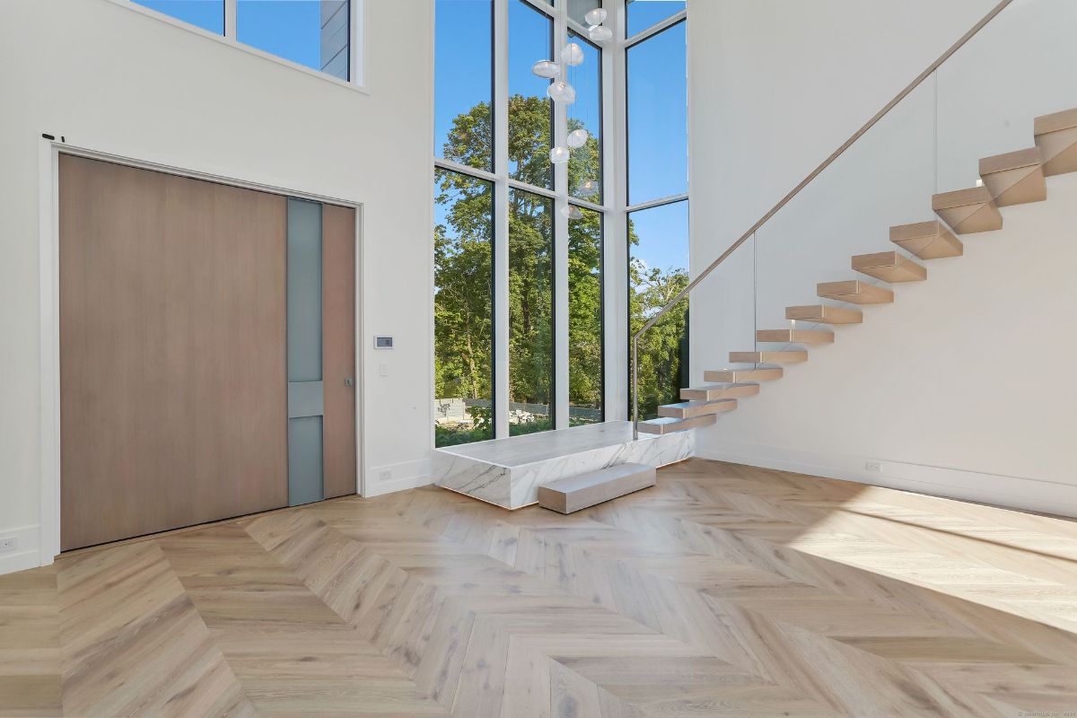 The floating staircase pairs seamlessly with herringbone hardwood floors, accentuating the open layout and sophisticated design.