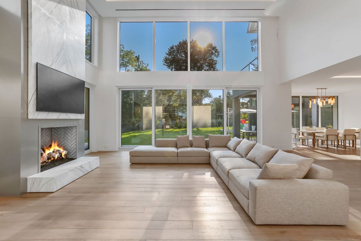 Sunlight streams through expansive windows, illuminating the spacious living area and adjacent dining space.