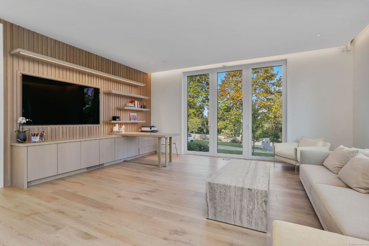 A sophisticated study space features built-in cabinetry, large glass doors, and serene views of the landscaped grounds.