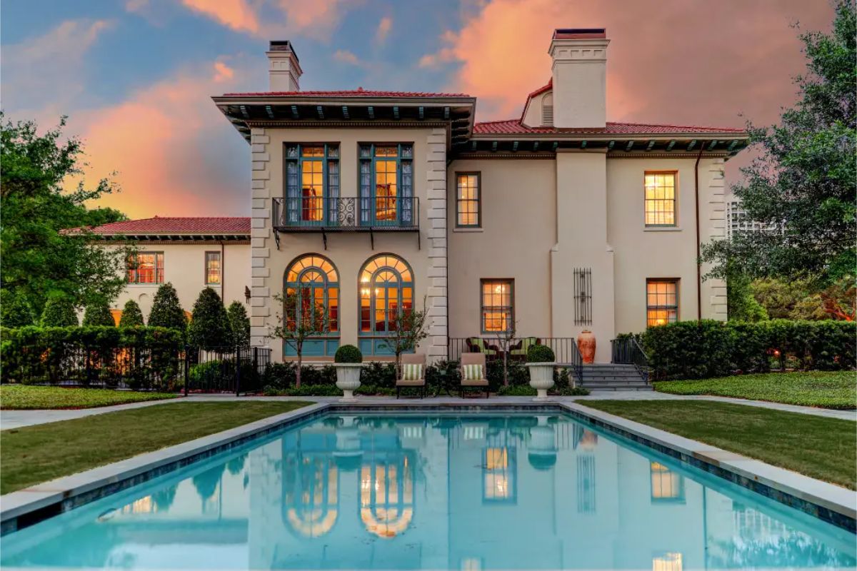 Two-story Mediterranean Revival home with arched windows, wrought iron balcony, and terracotta tile roof.