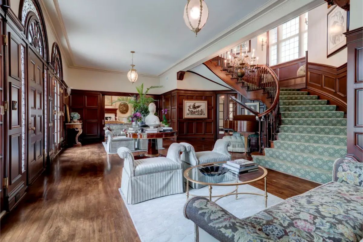 Living area with rich wood-paneled walls and a curved staircase as a focal point.