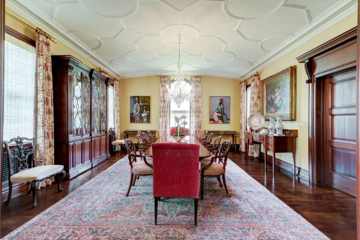 Elongated dining room with a detailed coffered ceiling and a large central chandelier.