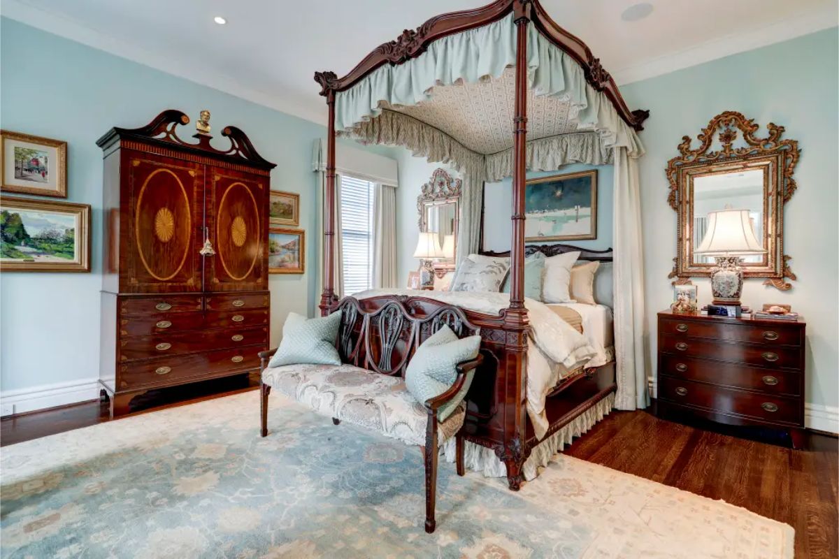 Bedroom featuring a four-poster canopy bed with intricate wood carvings and fabric drapery.