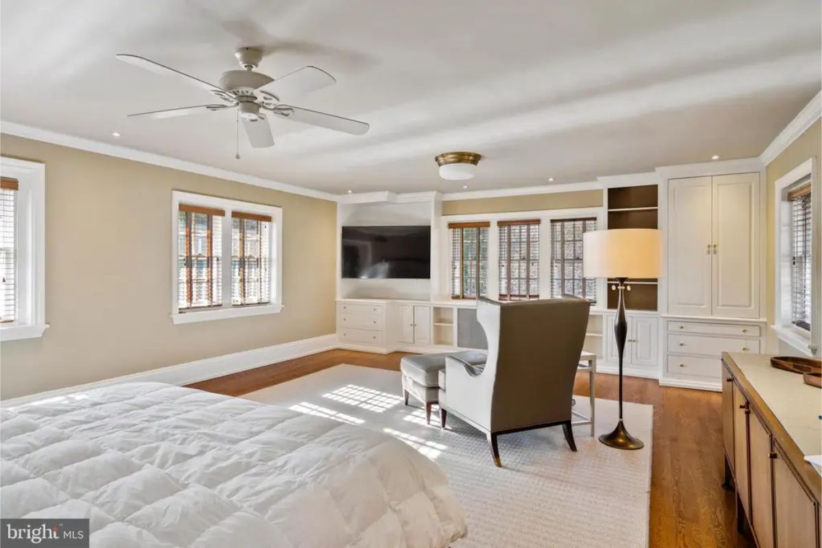 A large bedroom with neutral tones and hardwood floors offers a calm and inviting atmosphere.