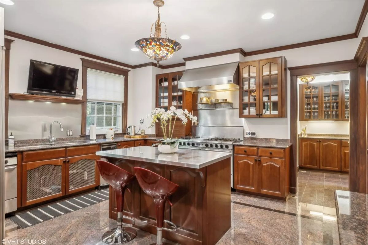 Central island with a stainless steel countertop and sleek bar stools provides a contemporary focal point.