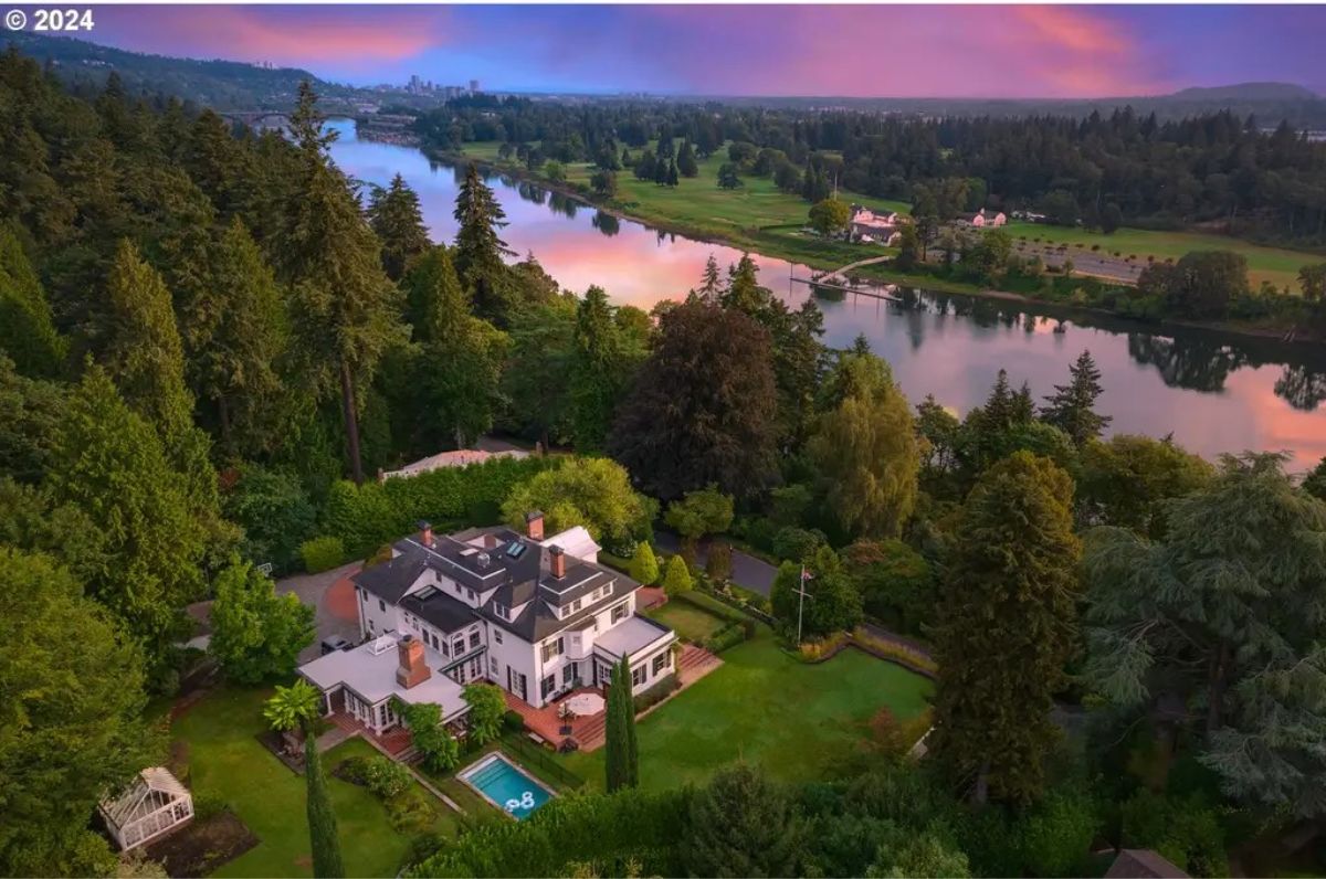 Expansive estate nestled among towering trees with a view of the Willamette River.