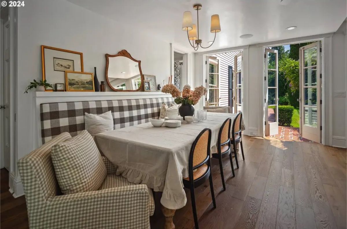 Dining area includes a table set for six, complemented by a plaid cushioned bench and matching armchair.