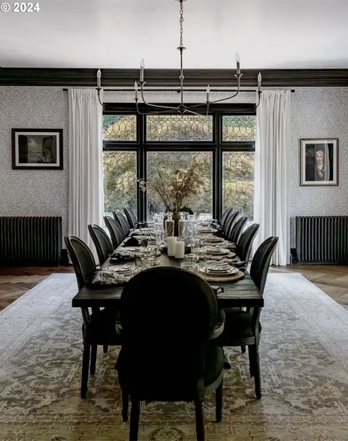 Dining room displays a long black table surrounded by high-back chairs, set with fine dinnerware.