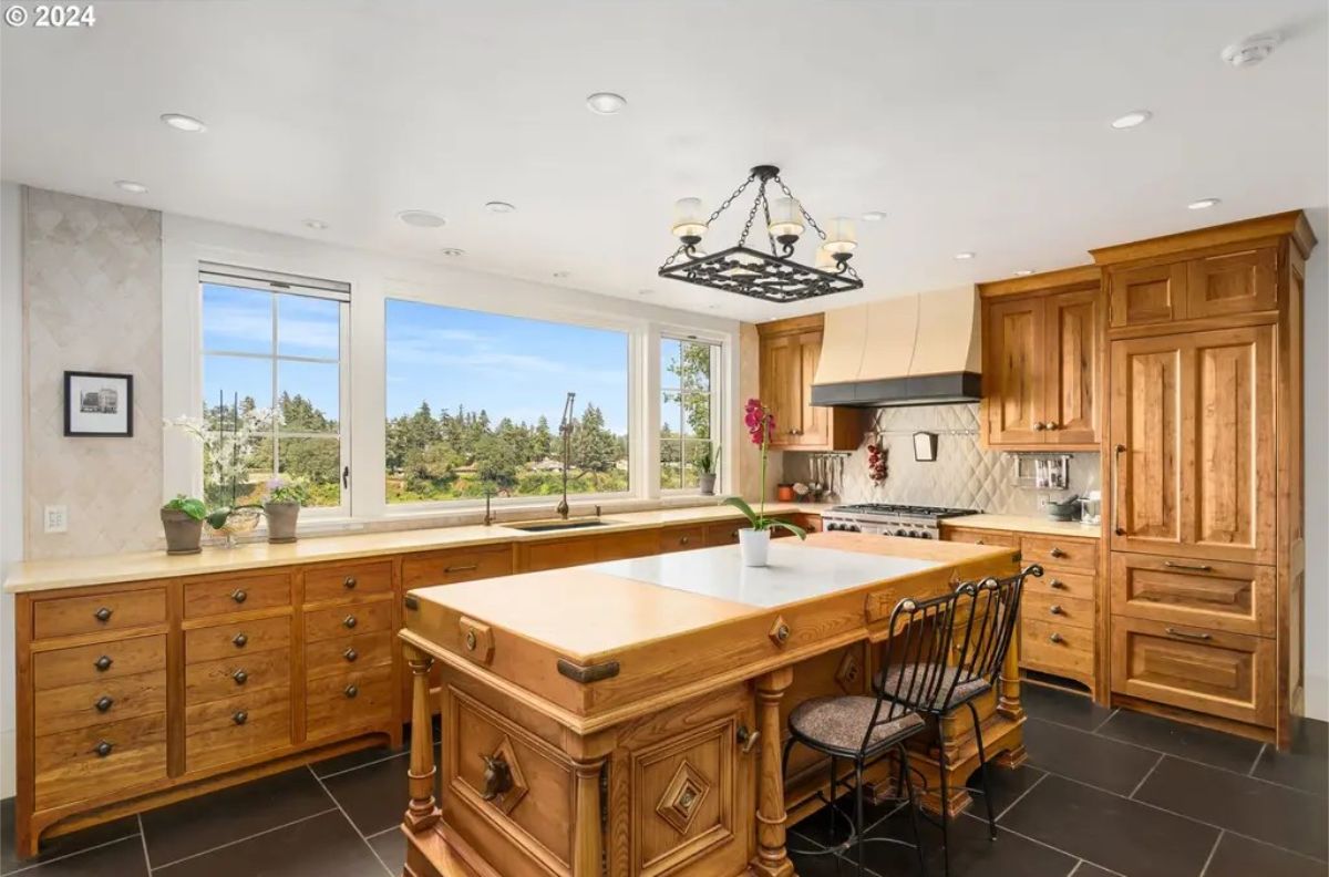 The kitchen features natural wood cabinetry and a large island with intricate detailing and a butcher-block top.