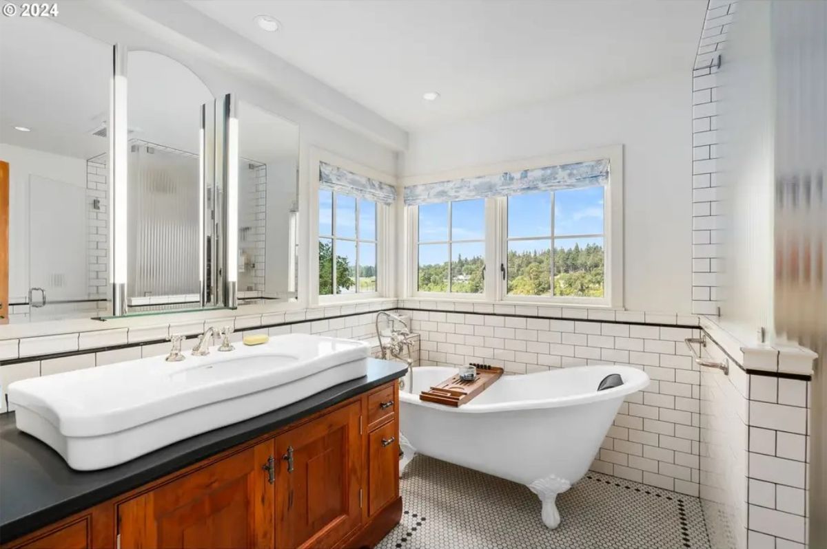 A freestanding clawfoot tub positioned near corner windows offering serene views of the landscape.