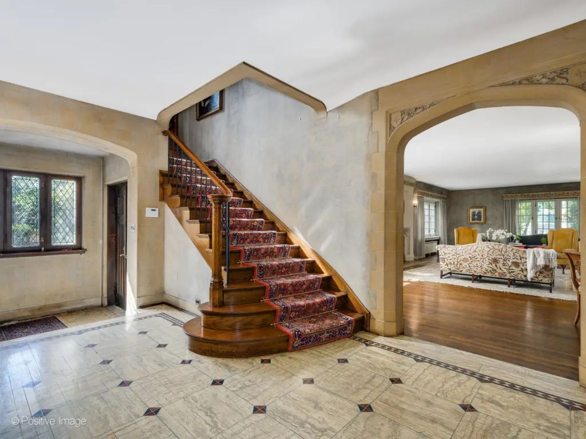 A curved wooden staircase with a patterned runner serves as the focal point of the foyer.