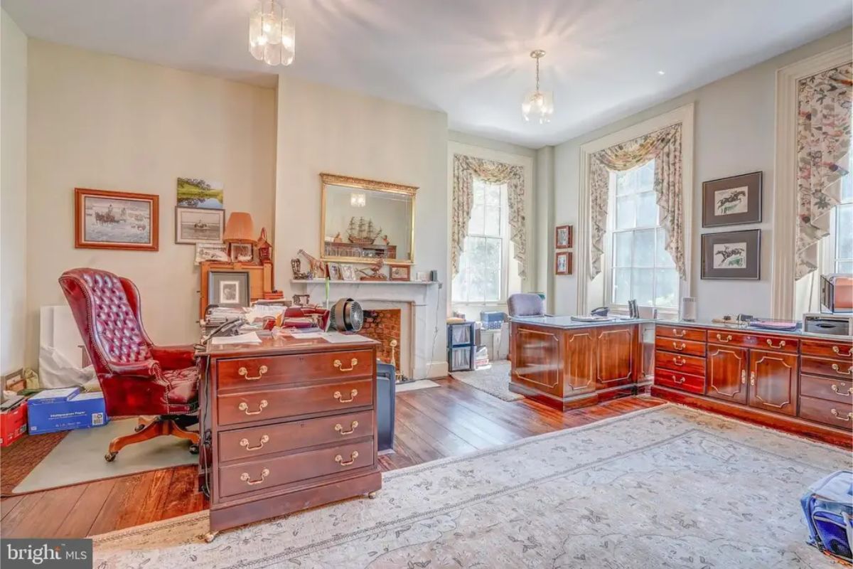 Home office featuring polished wooden desks, cabinetry, and a tufted leather chair.