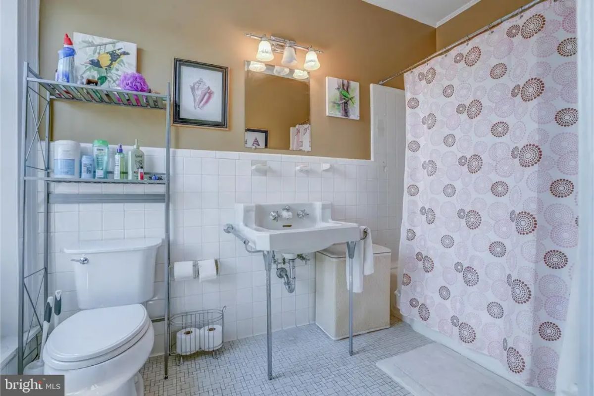 Bathroom with a pedestal sink, tiled walls, and a compact layout.