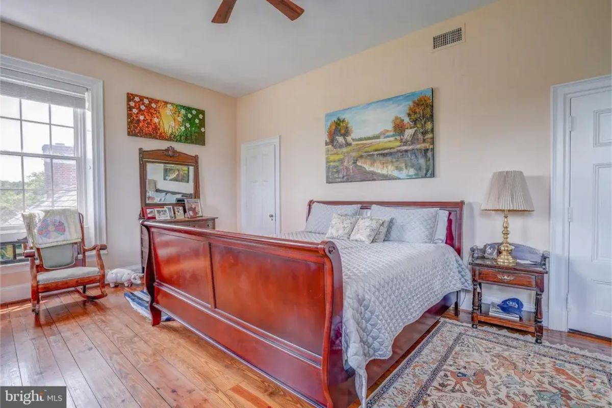 A polished wooden sleigh bed with soft, neutral bedding.