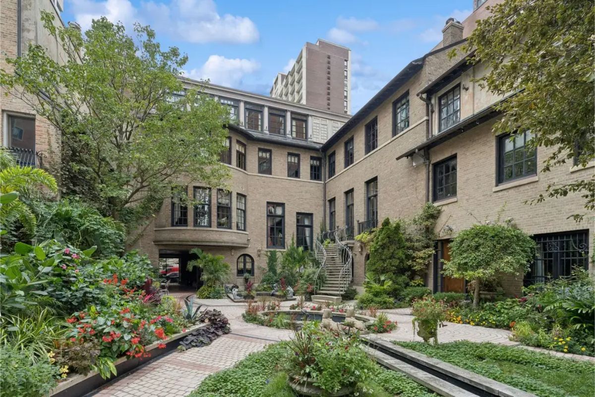 Enclosed courtyard with lush greenery, vibrant flowers, and paved walkways.