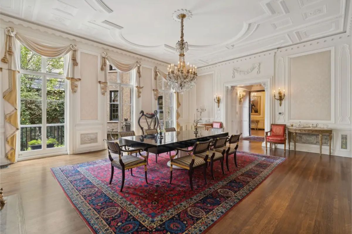 Spacious dining room with high ceilings, detailed crown molding, and a central crystal chandelier.