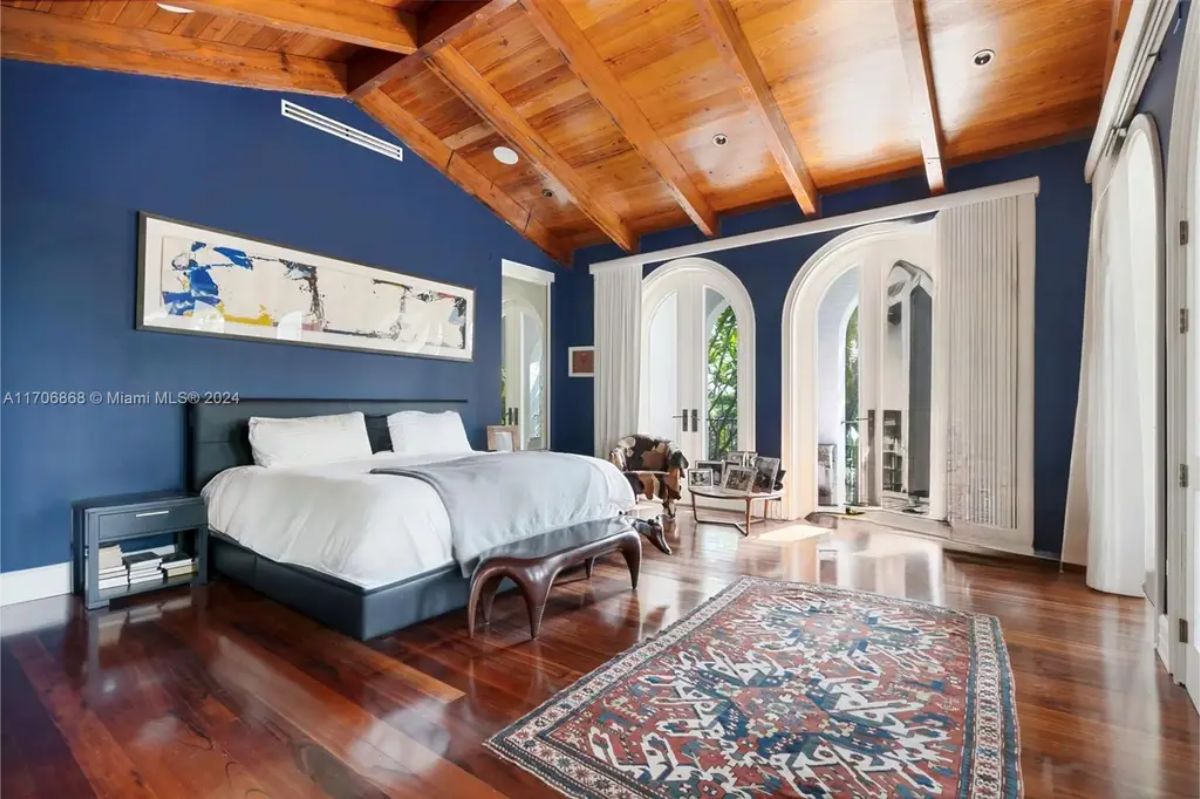 Bedroom with rich wooden floors and an exposed wooden beam ceiling for a warm and inviting feel.