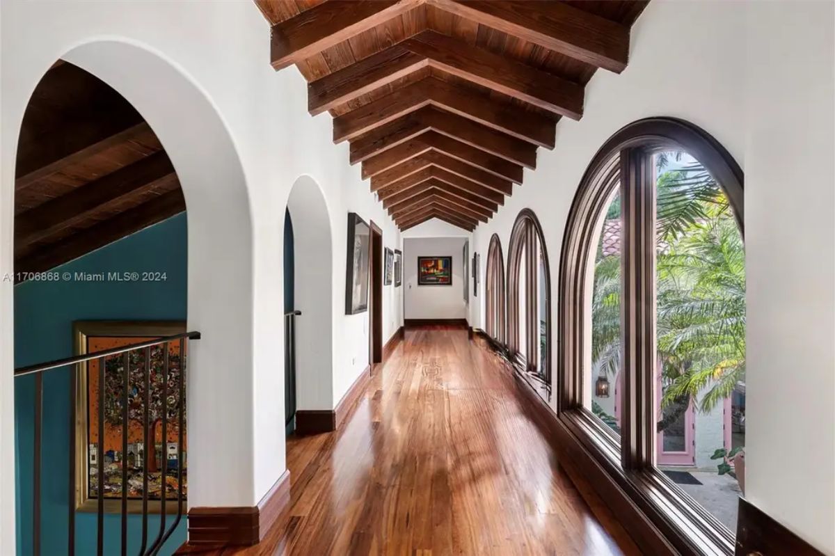 Long corridor with rich wooden floors and vaulted ceilings featuring exposed beams for a rustic yet refined aesthetic.