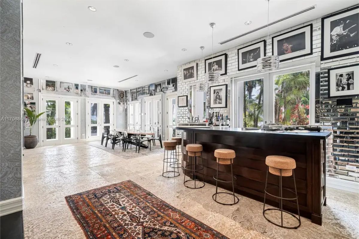 A sleek black bar with modern stools, complemented by bright white brick walls adorned with framed photography.