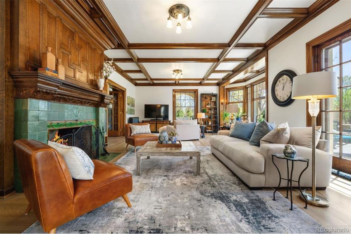 This beautifully restored living room features rich wood-paneled walls and a coffered ceiling, showcasing timeless craftsmanship.