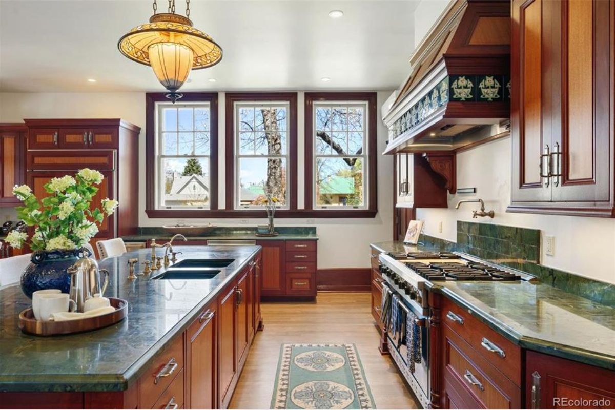 Rich wood cabinetry, complemented by striking green marble countertops and a custom tile backsplash.