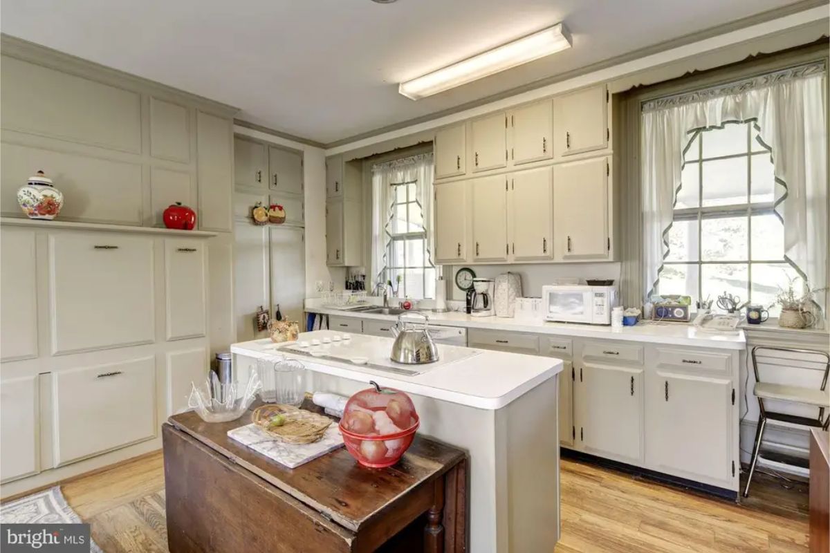 Kitchen with soft neutral cabinetry and a central island for food preparation.