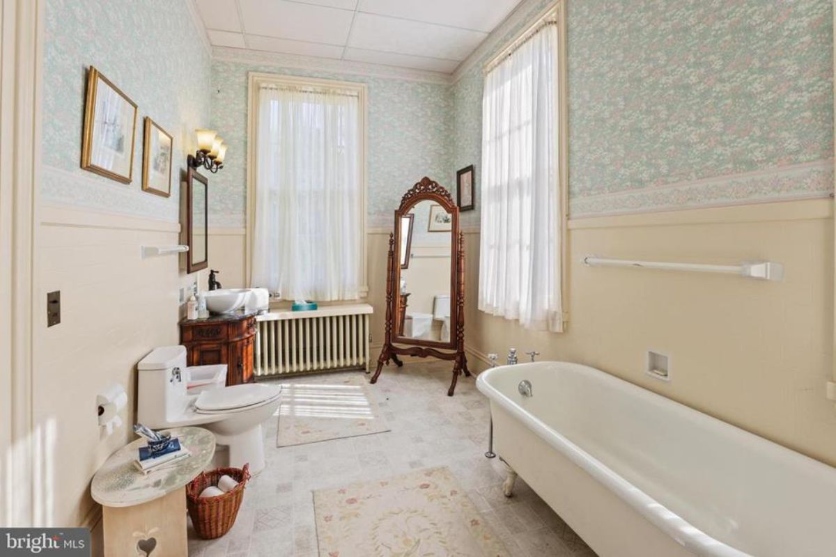 Spacious bathroom featuring a clawfoot tub and a pedestal sink housed in a carved wooden vanity.