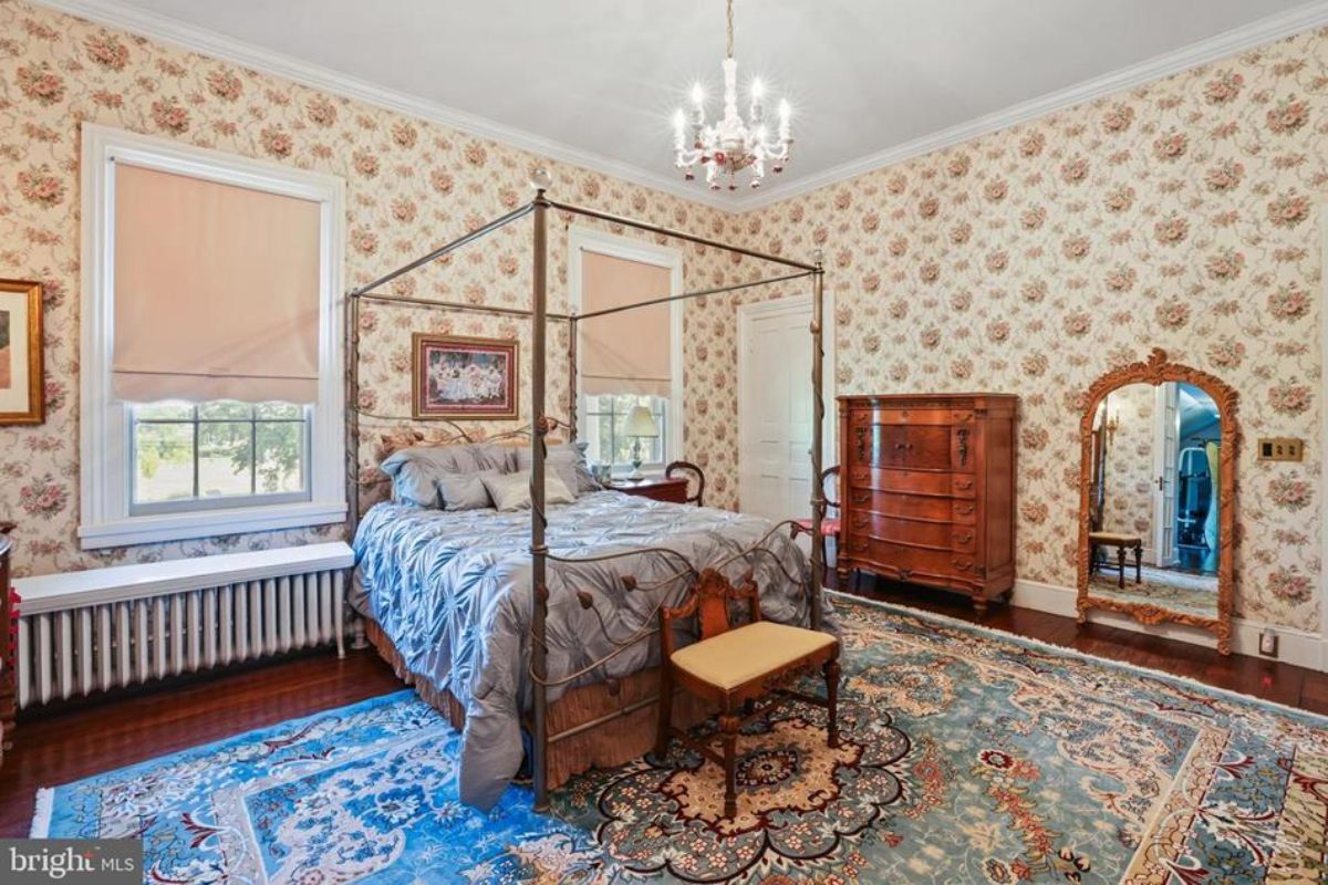 A metal canopy bed with decorative bedding and a blue patterned rug.