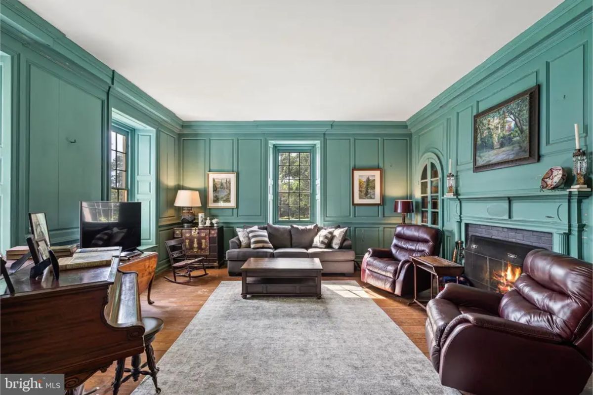 Living room with rich green paneling and a traditional fireplace as the focal point.