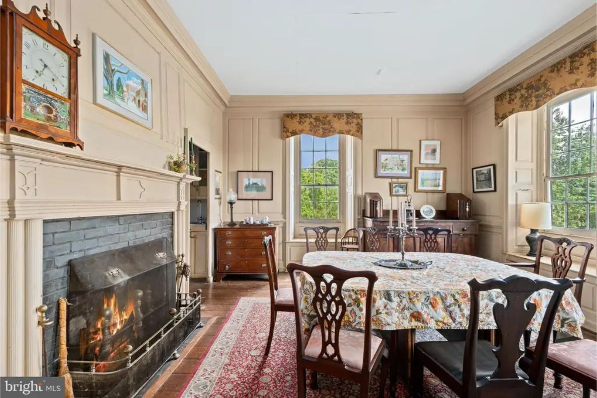 Paneled walls painted in soft tones surround a traditional wood-burning fireplace with a brick hearth.