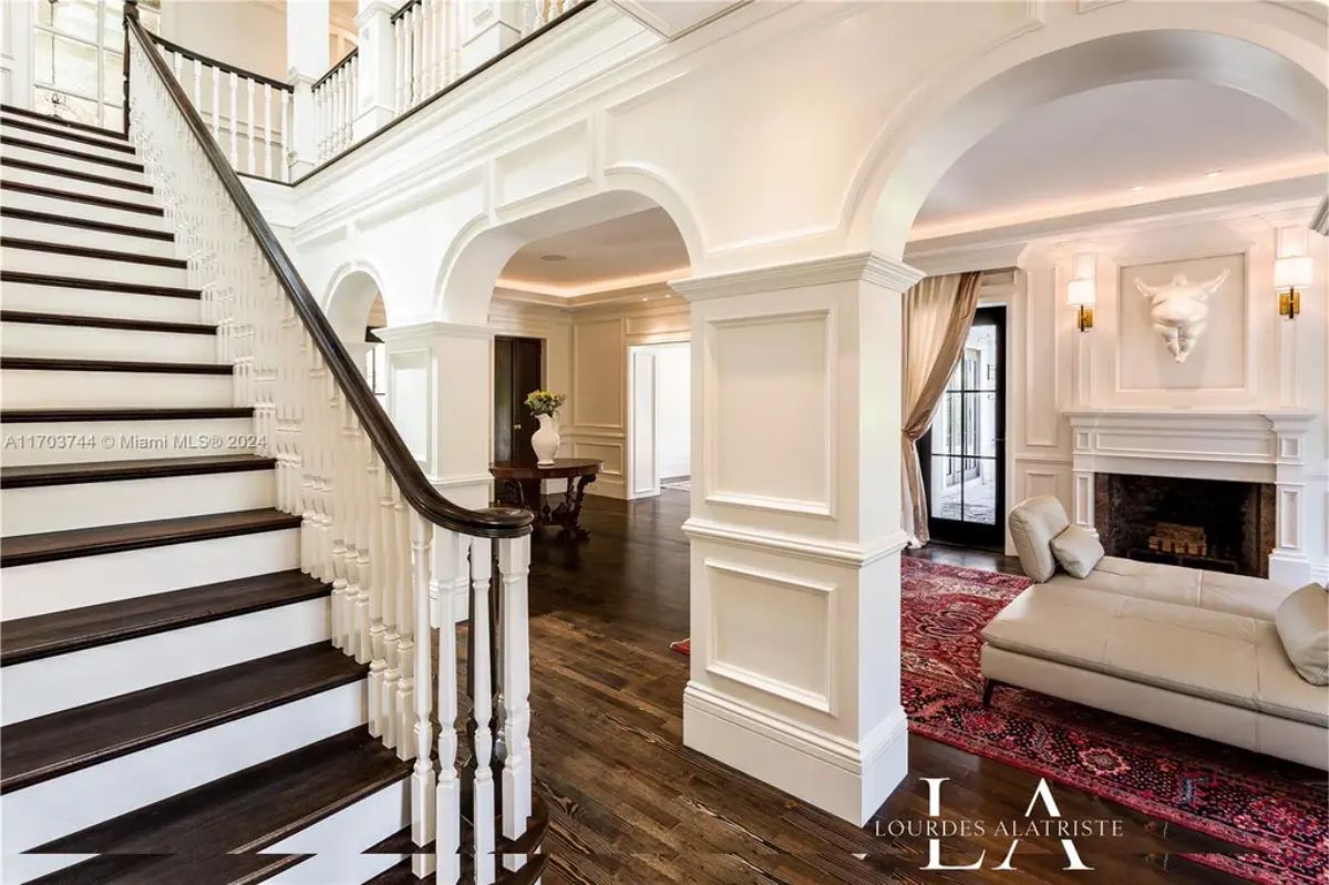 Grand staircase with dark wood steps and white balustrades leads to the upper level.