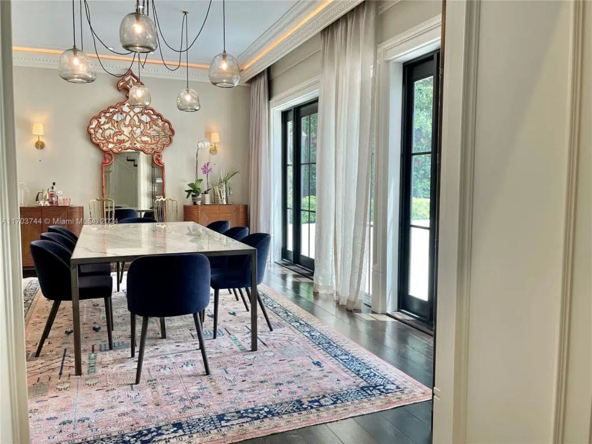 Dining room with a marble-top table surrounded by deep blue velvet chairs.