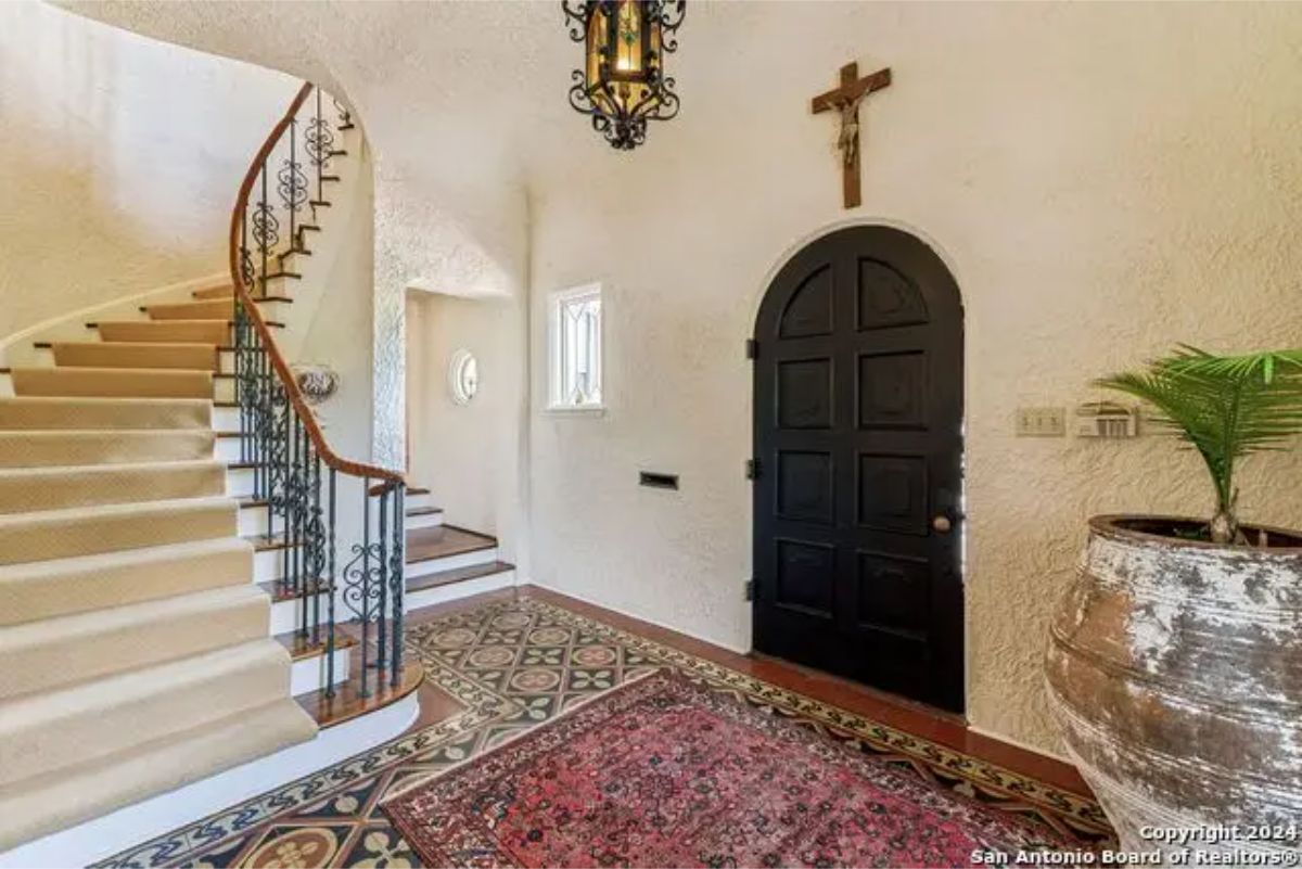 Entryway with textured walls and a custom black arched door.