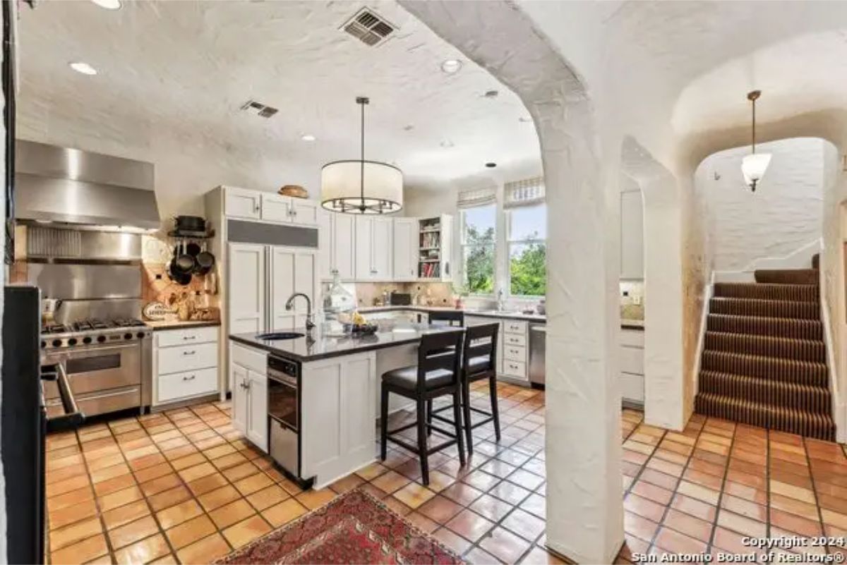 Kitchen with textured walls, terracotta tile flooring, and a large center island with seating.