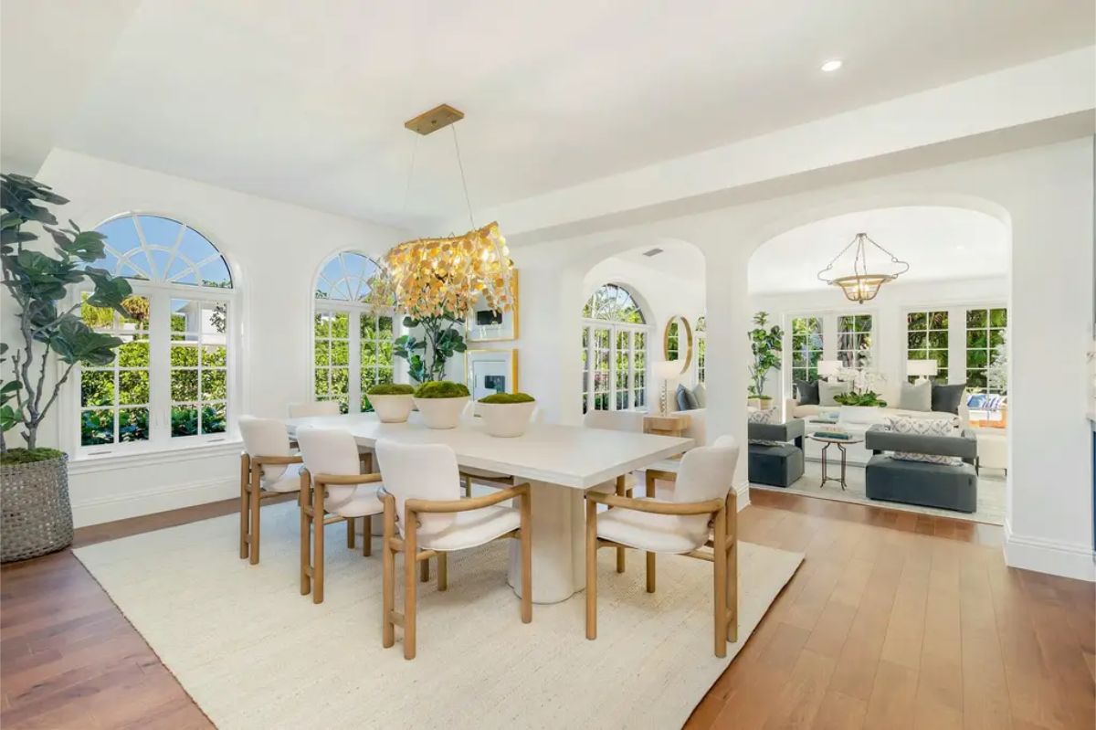 Open dining room with arched windows and an abundance of natural light, connecting to a living space through wide archways.