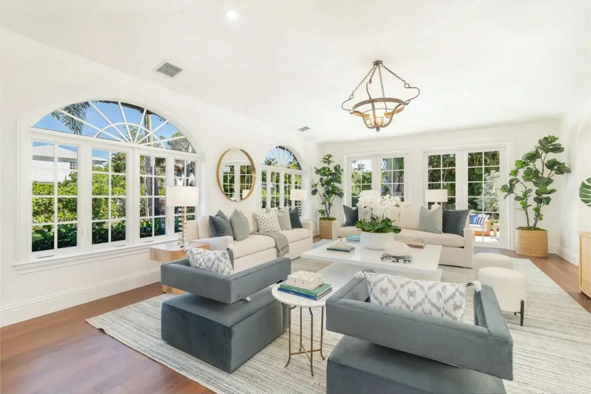 Spacious living room with arched windows and French doors allowing natural light and views of lush greenery.