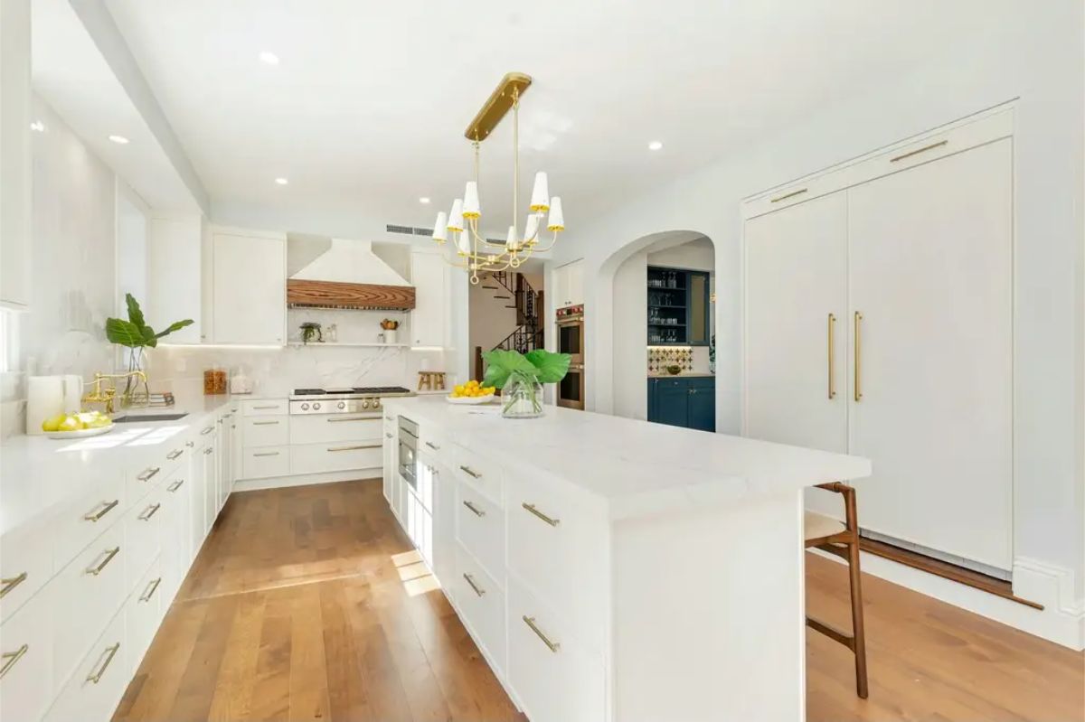 Kitchen with white cabinetry, marble countertops, and a large central island for food preparation and seating.