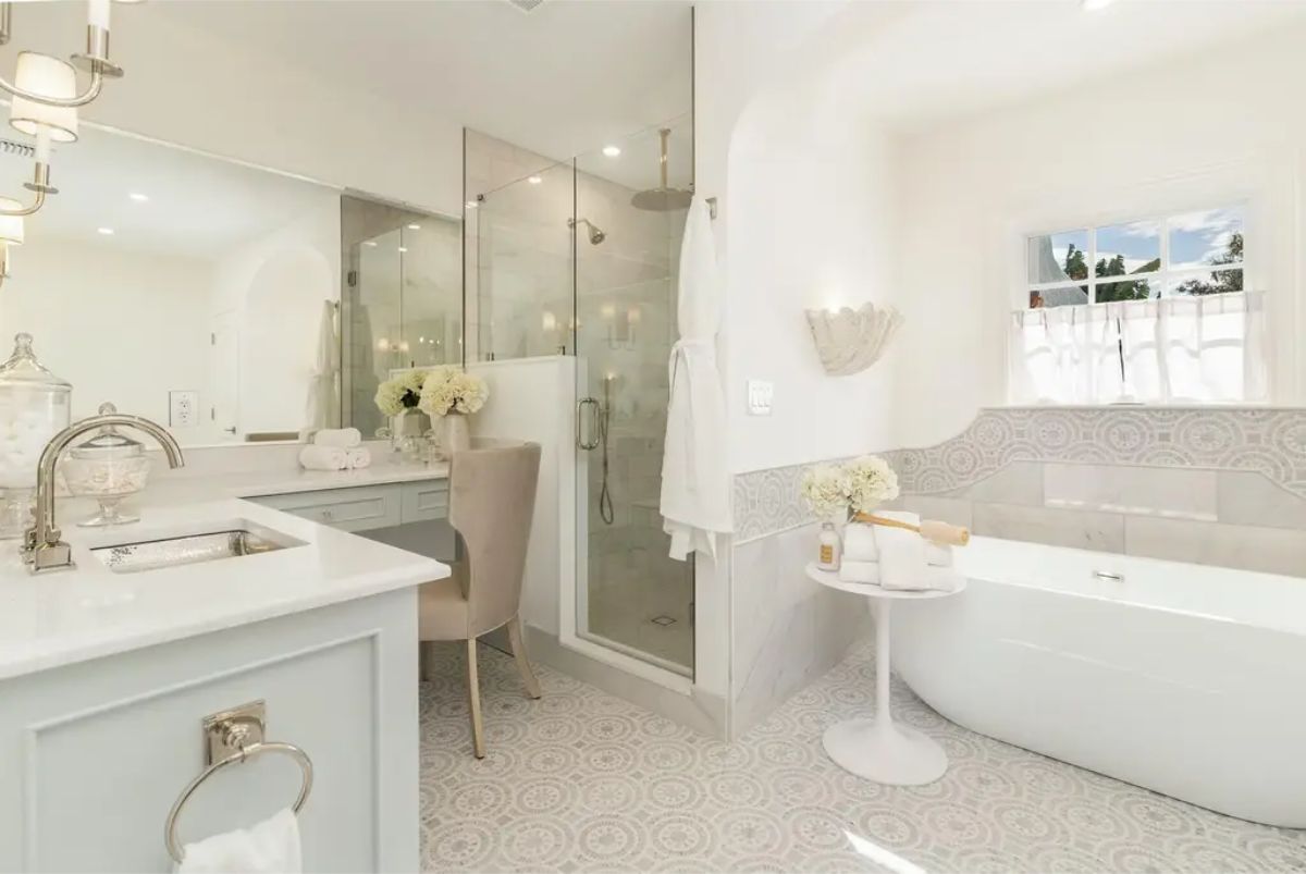 Freestanding soaking tub positioned next to a small side table and a window for natural light.