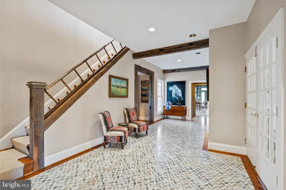 Hallway with exposed wooden beams and a custom patterned tile floor.