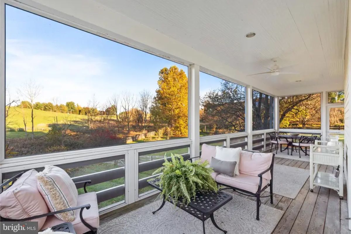 Relaxing screened-in porch with views of rolling fields and mature trees.