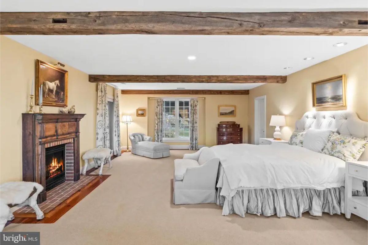 Large bedroom with a fireplace framed by a wooden mantel and brick hearth.