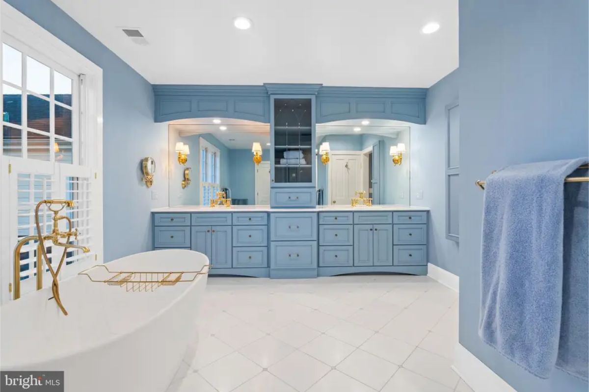 Bathroom with soft blue cabinetry and walls, complemented by gold accents.