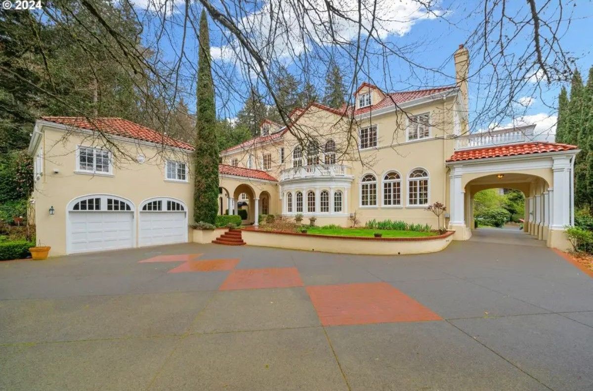 A Mediterranean-style home showcases stucco walls and red tile roofing, surrounded by landscaped greenery.