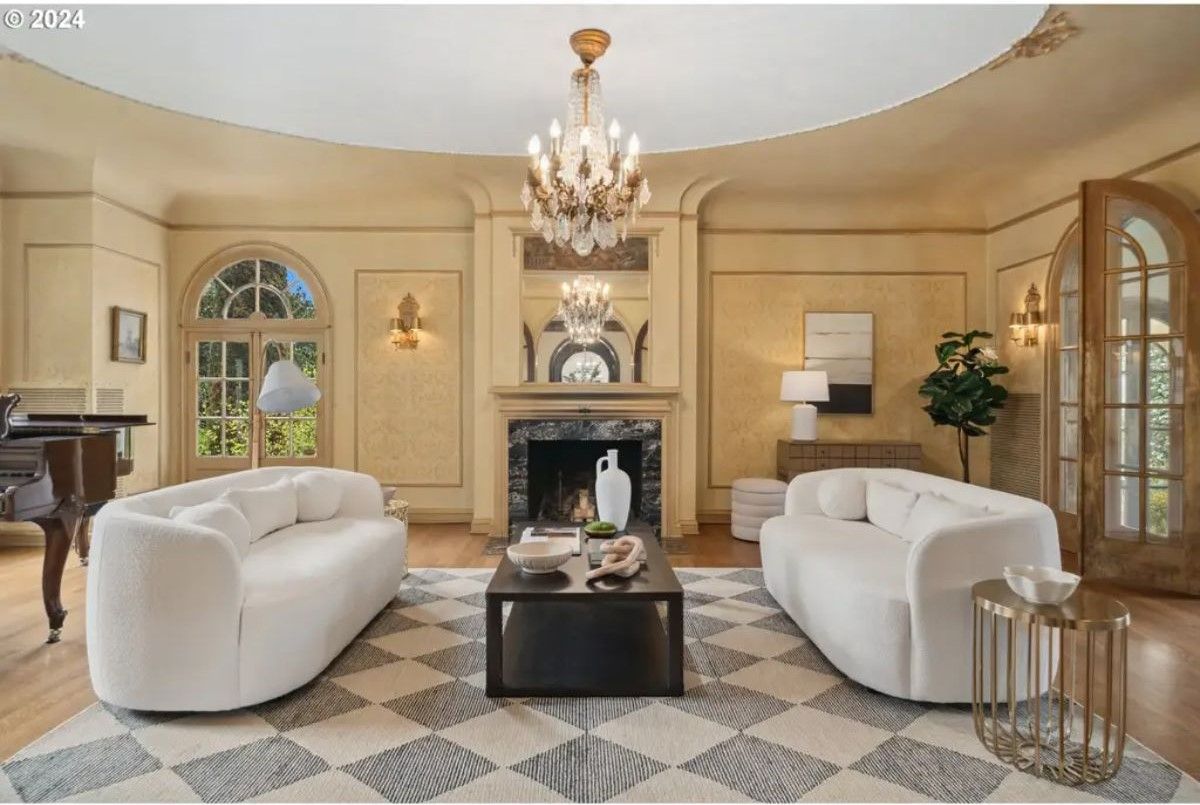 Symmetrical layout with two curved white sofas centered around a black coffee table on a checkered rug.